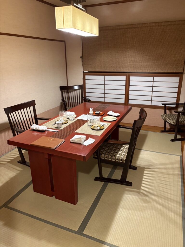 鴨川館・畳敷きの個室食事処。朱塗りのテーブルと障子の光が落ち着いた和の空間を演出